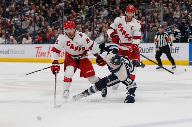 Dec 31, 2024; Columbus, Ohio, USA; Columbus Blue Jackets center Adam Fantilli (19) falls to the ice after a check from Carolina Hurricanes left wing William Carrier (28) during the first period at Nationwide Arena. Mandatory Credit: Russell LaBounty-Imagn Images