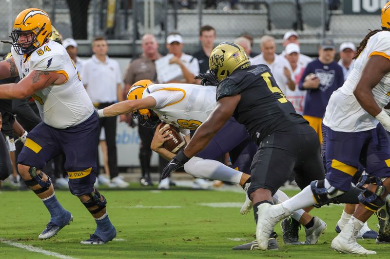 Aug 31, 2023; Orlando, Florida, USA; Kent State Golden Flashes quarterback Michael Alaimo (18) is sacked by UCF Knights defensive tackle Ricky Barber (5) during the first quarter at FBC Mortgage Stadium. Mandatory Credit: Mike Watters-USA TODAY Sports battle for the ball