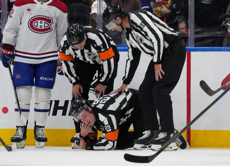 Sep 27, 2025; Toronto, Ontario, CAN; Refeeree Carter Sandluck (29) gets assistance after crashing into the boards during the third period of a game between the Montreal Canadiens and Toronto Maple Leafs at Scotiabank Arena. Mandatory Credit: John E. Sokolowski-Imagn Images