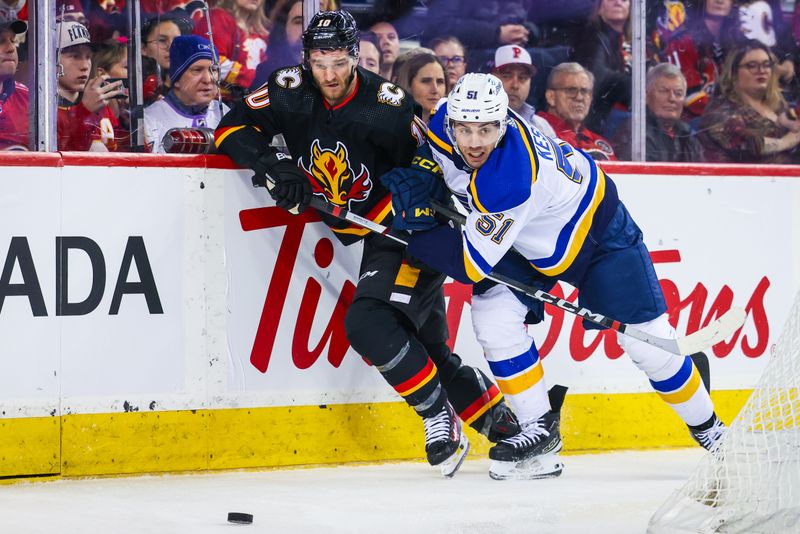 Jan 23, 2024; Calgary, Alberta, CAN; Calgary Flames center Jonathan Huberdeau (10) and St. Louis Blues defenseman Matthew Kessel (51) battles for the puck during the second period at Scotiabank Saddledome. Mandatory Credit: Sergei Belski-USA TODAY Sports