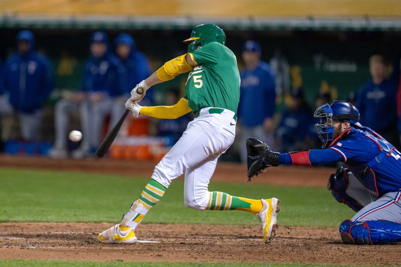 Sep 24, 2024; Oakland, California, USA; Oakland Athletics shortstop Jacob Wilson (5) hits a RBI single to right field scoring Oakland Athletics second baseman Zack Gelof (not pictured) for the winning run against the Texas Rangers during the ninth inning at Oakland-Alameda County Coliseum. Mandatory Credit: Neville E. Guard-Imagn Images