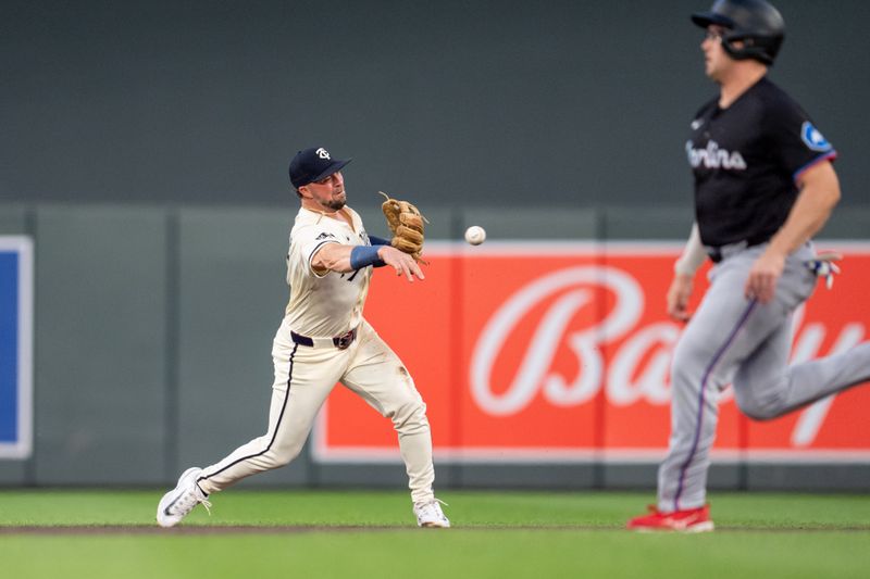 Sep 26, 2024; Minneapolis, Minnesota, USA; Minnesota Twins second base Kyle Farmer (12) throws to first for the third out of the first inning as Miami Marlins first base Jonah Bride (41) runs to second base at Target Field. Mandatory Credit: Matt Blewett-Imagn Images