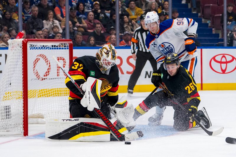 Nov 9, 2024; Vancouver, British Columbia, CAN;  Vancouver Canucks goalie Kevin Lankinen (32) makes a save in front of defenseman Erik Brannstrom (26) and Edmonton Oilers forward Corey Perry (90) during the third period at Rogers Arena. Mandatory Credit: Bob Frid-Imagn Images