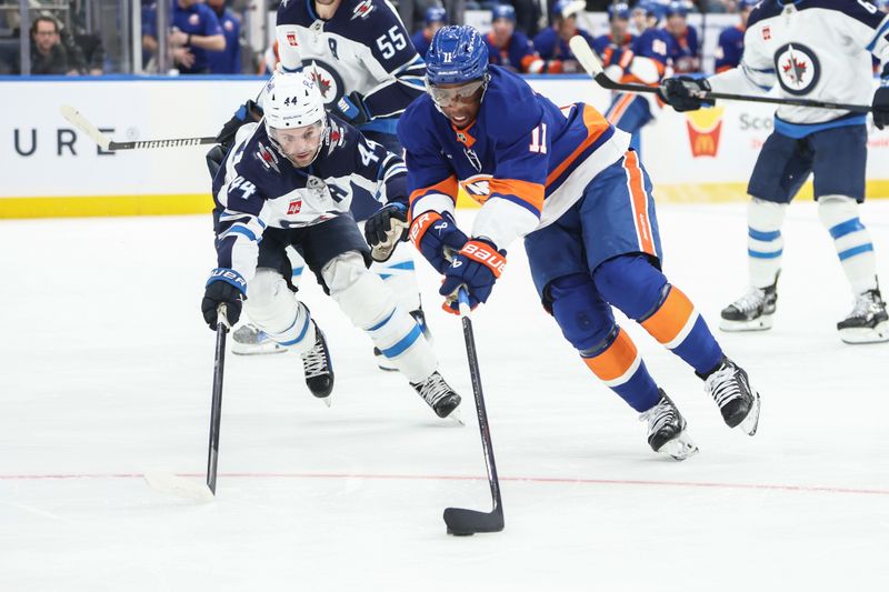 Mar 4, 2025; Elmont, New York, USA;  Winnipeg Jets defenseman Josh Morrissey (44) and New York Islanders left wing Anthony Duclair (11) battle for control of the puck in the second period at UBS Arena. Mandatory Credit: Wendell Cruz-Imagn Images