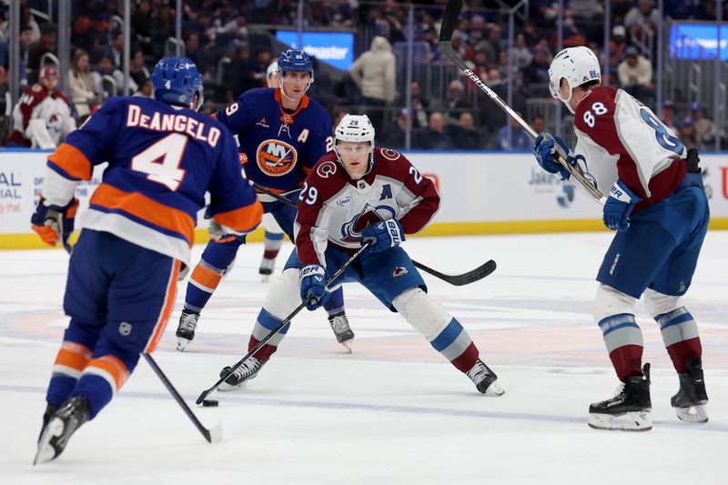 Jan 28, 2025; Elmont, New York, USA; Colorado Avalanche center Nathan MacKinnon (29) skates with the puck against New York Islanders defenseman Tony DeAngelo (4) during the third period at UBS Arena. Mandatory Credit: Brad Penner-Imagn Images