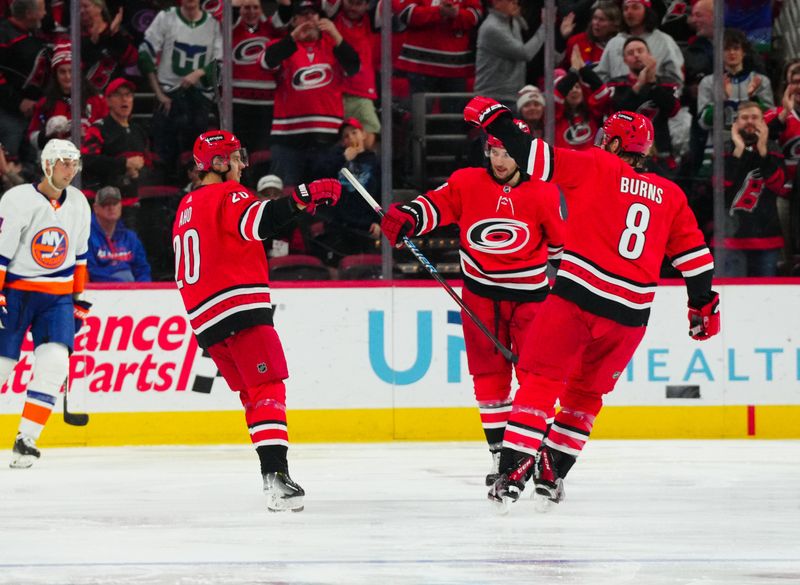 Dec 23, 2023; Raleigh, North Carolina, USA; Carolina Hurricanes center Sebastian Aho (20) celebrates his goal with left wing Michael Bunting (58) and defenseman Brent Burns (8) against the New York Islanders during the second period at PNC Arena. Mandatory Credit: James Guillory-USA TODAY Sports