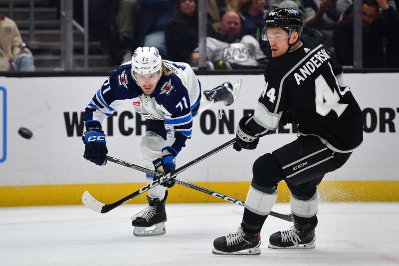 Dec 13, 2023; Los Angeles, California, USA; Winnipeg Jets left wing Axel Jonsson-Fjallby (71) passes the puck against Los Angeles Kings defenseman Mikey Anderson (44)  during the third period at Crypto.com Arena. Mandatory Credit: Gary A. Vasquez-USA TODAY Sports