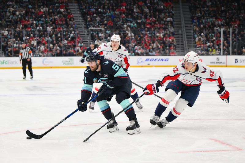 Jan 23, 2025; Seattle, Washington, USA; Seattle Kraken center Shane Wright (51) plays the puck while defended by Washington Capitals defenseman Martin Fehervary (42) during the third period at Climate Pledge Arena. Mandatory Credit: Steven Bisig-Imagn Images