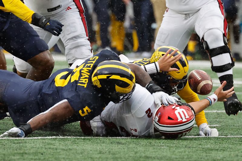 Oct 14, 2023; Ann Arbor, Michigan, USA; Indiana Hoosiers quarterback Tayven Jackson (2) fumbles as he is sacked by Michigan Wolverines linebacker Michael Barrett (23) and defensive end Josaiah Stewart (5) in the second half against the Michigan Wolverines at Michigan Stadium. Mandatory Credit: Rick Osentoski-USA TODAY Sports