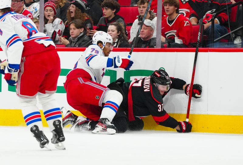 Nov 27, 2024; Raleigh, North Carolina, USA;  New York Rangers defenseman K'Andre Miller (79) checks Carolina Hurricanes right wing Andrei Svechnikov (37) during the first period at Lenovo Center. Mandatory Credit: James Guillory-Imagn Images