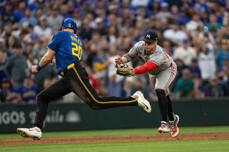 Jun 28, 2024; Seattle, Washington, USA; Minnesota Twins third baseman Jose Miranda (64) attempts to tag Seattle Mariners pinch runner Luke Raley (20) during the eighth inning at T-Mobile Park. Mandatory Credit: Stephen Brashear-USA TODAY Sports