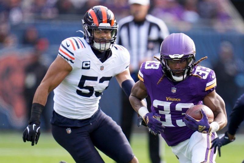 Minnesota Vikings running back Aaron Jones (33) runs past Chicago Bears linebacker T.J. Edwards (53) during the first half of an NFL football game Sunday, Nov. 24, 2024, in Chicago. (AP Photo/Erin Hooley)