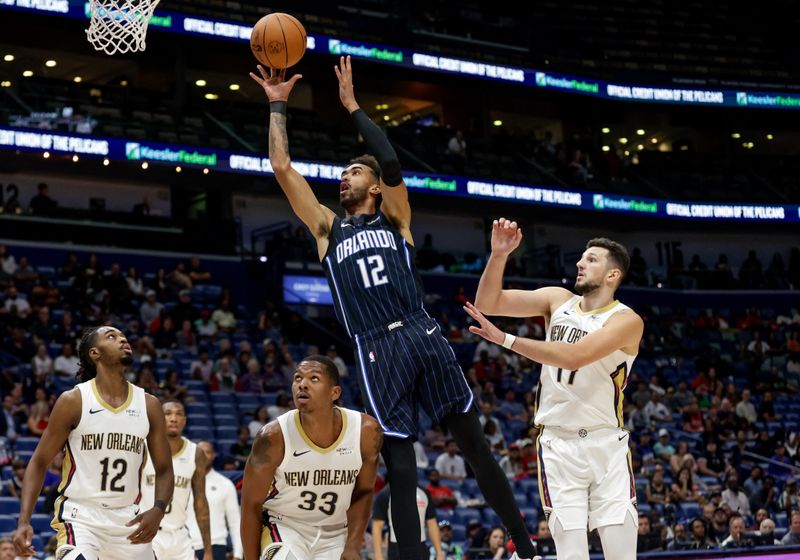 NEW ORLEANS, LOUISIANA - OCTOBER 7:  Trevelin Queen #12 of the Orlando Magic shoots over Karlo Matkovic #17, Malcolm Hill #33 and Antonio Reeves #12 of the New Orleans Pelicans during the second half of a preseason game at the Smoothie King Center on October 7, 2024 in New Orleans, Louisiana. NOTE TO USER: User expressly acknowledges and agrees that, by downloading and or using this photograph, User is consenting to the terms and conditions of the Getty Images License Agreement. (Photo by Derick E. Hingle/Getty Images)