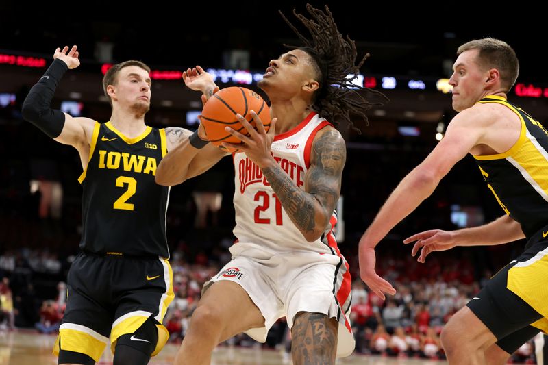 Jan 27, 2025; Columbus, Ohio, USA;  Ohio State Buckeyes forward Devin Royal (21) takes the ball to the basket as Iowa Hawkeyes guard Brock Harding (2) defends during the second half at Value City Arena. Mandatory Credit: Joseph Maiorana-Imagn Images