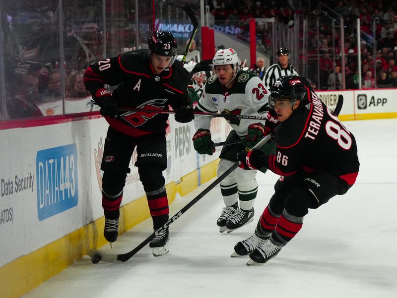 Jan 21, 2024; Raleigh, North Carolina, USA; Carolina Hurricanes left wing Teuvo Teravainen (86) and center Sebastian Aho (20) skate with the puck past Minnesota Wild center Marco Rossi (23) during the first period at PNC Arena. Mandatory Credit: James Guillory-USA TODAY Sports