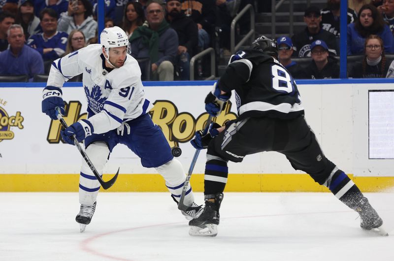 Nov 30, 2024; Tampa, Florida, USA; Toronto Maple Leafs center John Tavares (91) skates with the puck as Tampa Bay Lightning defenseman Erik Cernak (81) defends during the second period at Amalie Arena. Mandatory Credit: Kim Klement Neitzel-Imagn Images