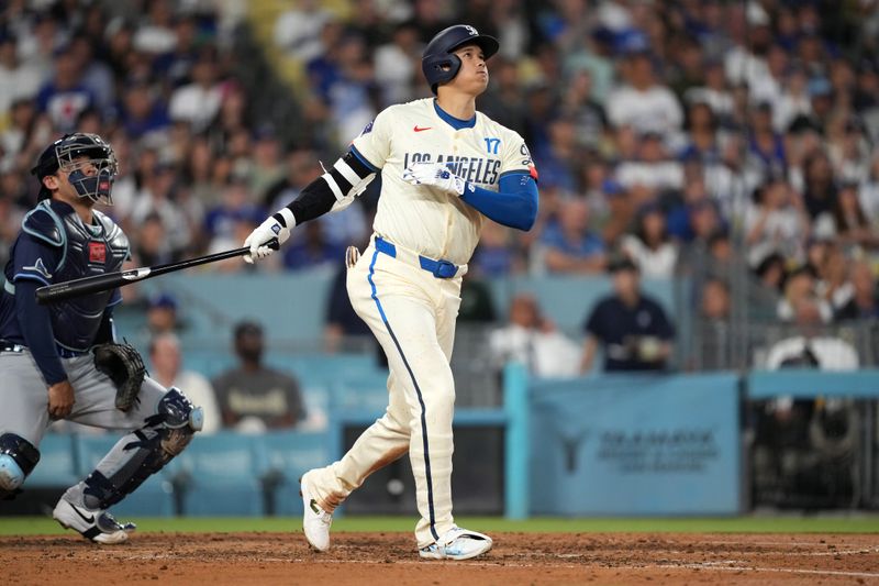 Aug 24, 2024; Los Angeles, California, USA; Los Angeles Dodgers designated hitter Shohei Ohtani (17) hits a two-run home run in the fifth inning as Tampa Bay Rays catcher Alex Jackson (28) watches at Dodger Stadium. Mandatory Credit: Kirby Lee-USA TODAY Sports