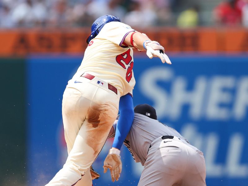 Jul 31, 2024; Philadelphia, Pennsylvania, USA;  Philadelphia Phillies third base Alec Bohm (28) slides into second base past New York Yankees shortstop Anthony Volpe (11) for a double during the eighth inning at Citizens Bank Park. Mandatory Credit: Bill Streicher-USA TODAY Sports