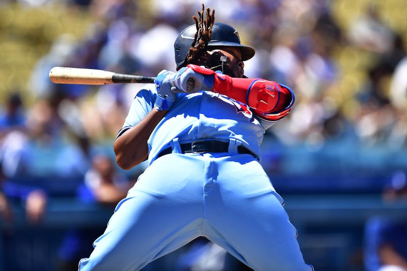 Jul 26, 2023; Los Angeles, California, USA; Toronto Blue Jays first baseman Vladimir Guerrero Jr. (27) moves to avoid inside pitch from Los Angeles Dodgers starting pitcher Tony Gonsolin (26) during the fifth inning at Dodger Stadium. Mandatory Credit: Gary A. Vasquez-USA TODAY Sports