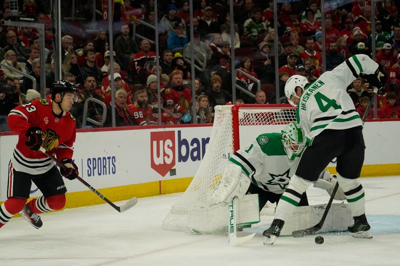 Nov 27, 2024; Chicago, Illinois, USA; Dallas Stars defenseman Miro Heiskanen (4) clears the puck from Chicago Blackhawks center Philipp Kurashev (23) during the first period at United Center. Mandatory Credit: David Banks-Imagn Images