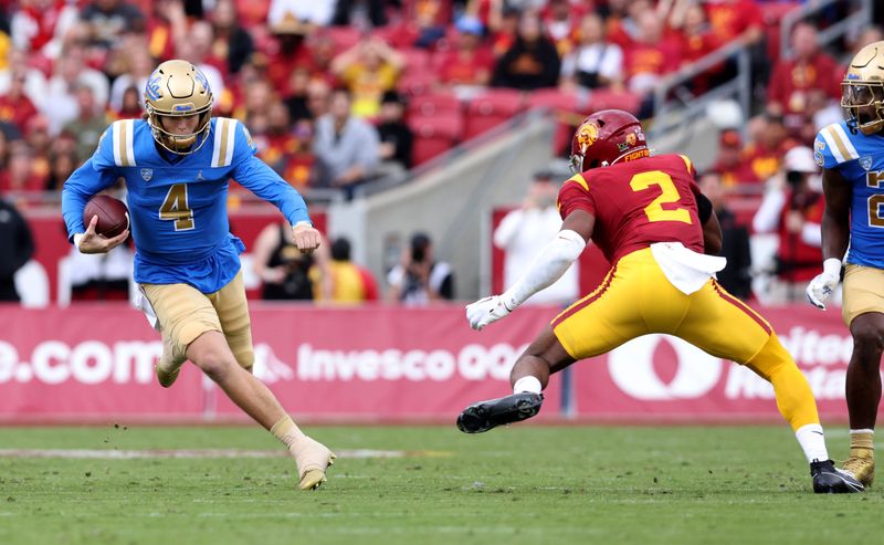 Nov 18, 2023; Los Angeles, California, USA; UCLA Bruins quarterback Ethan Garbers (4) scrambles against USC Trojans defensive end Romello Height (2) during the first quarter at United Airlines Field at Los Angeles Memorial Coliseum. Mandatory Credit: Jason Parkhurst-USA TODAY Sports