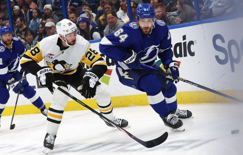 Dec 6, 2023; Tampa, Florida, USA; Tampa Bay Lightning center Tyler Motte (64) skates with the puck and Pittsburgh Penguins defenseman Marcus Pettersson (28) defends during the third period at Amalie Arena. Mandatory Credit: Kim Klement Neitzel-USA TODAY Sports