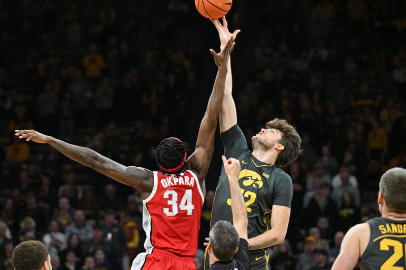 Feb 2, 2024; Iowa City, Iowa, USA; Iowa Hawkeyes forward Owen Freeman (32) and Ohio State Buckeyes center Felix Okpara (34) battle for the opening tipoff during the first half at Carver-Hawkeye Arena. Mandatory Credit: Jeffrey Becker-USA TODAY Sports