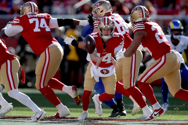 San Francisco 49ers quarterback Sam Darnold (14) pitches the ball to running back Elijah Mitchell (25) during an NFL football game against the Los Angeles Rams, Monday, Jan. 7, 2024, in Santa Clara, Calif. (AP Photo/Scot Tucker)