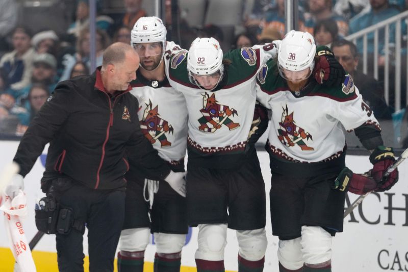 Dec 21, 2023; San Jose, California, USA; Arizona Coyotes left wing Jason Zucker (16) and center Liam O'Brien (38) assist center Logan Cooley (92) back up after colliding into the wall during the third period against the San Jose Sharks at SAP Center at San Jose. Mandatory Credit: Stan Szeto-USA TODAY Sports