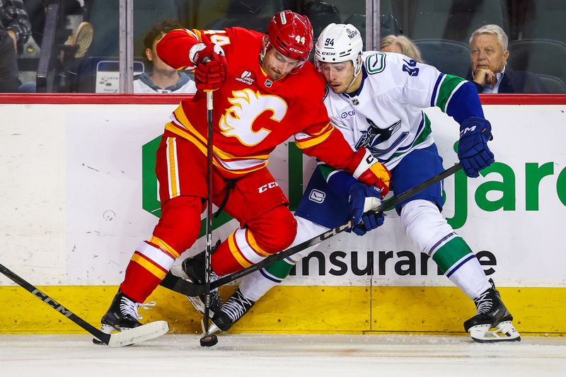 Oct 1, 2025; Calgary, Alberta, CAN; Calgary Flames defenseman Joel Hanley (44) and Vancouver Canucks center Linus Karlsson (94) battles for the puck during the first period at Scotiabank Saddledome. Mandatory Credit: Sergei Belski-Imagn Images