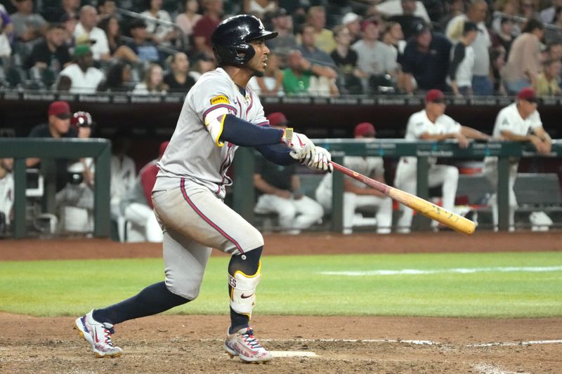 Jul 8, 2024; Phoenix, Arizona, USA; Atlanta Braves second base Ozzie Albies (1) hits an RBI sacrifice fly out against the Arizona Diamondbacks in the tenth inning at Chase Field. Mandatory Credit: Rick Scuteri-USA TODAY Sports