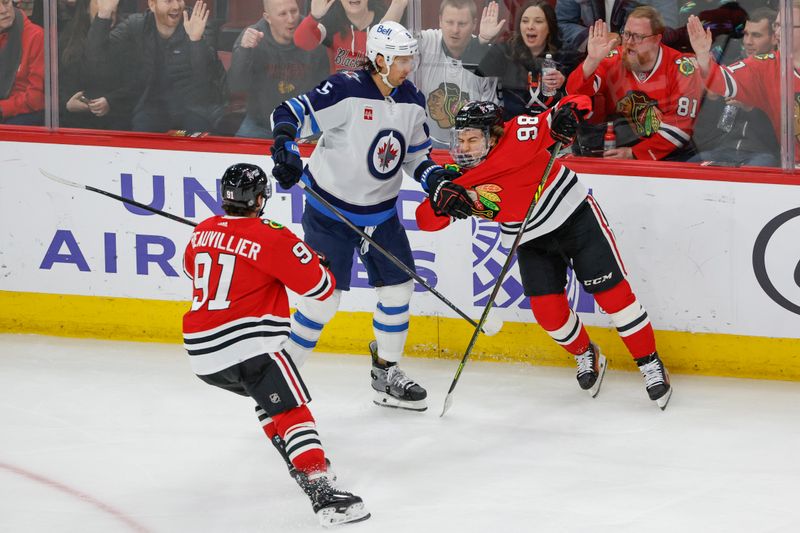 Feb 23, 2024; Chicago, Illinois, USA; Winnipeg Jets defenseman Brenden Dillon (5) pushes Chicago Blackhawks center Connor Bedard (98) during the third period at United Center. Mandatory Credit: Kamil Krzaczynski-USA TODAY Sports