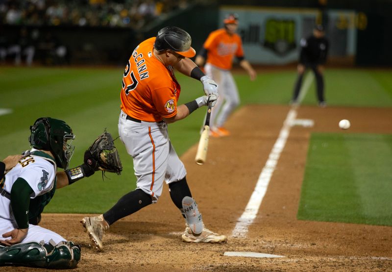 Aug 19, 2023; Oakland, California, USA; Baltimore Orioles catcher James McCann (27) connects for a two-RBI single against the Oakland Athletics during the 10th inning at Oakland-Alameda County Coliseum. Mandatory Credit: D. Ross Cameron-USA TODAY Sports