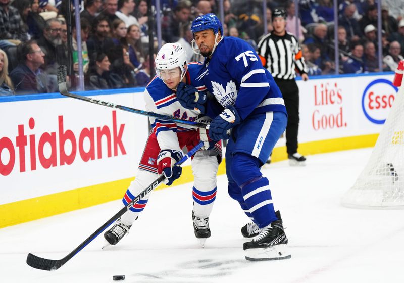 Oct 19, 2024; Toronto, Ontario, CAN; Toronto Maple Leafs right wing Ryan Reaves (75) battles for the puck with New York Rangers defenseman Braden Schneider (4) during the first period at Scotiabank Arena. Mandatory Credit: Nick Turchiaro-Imagn Images