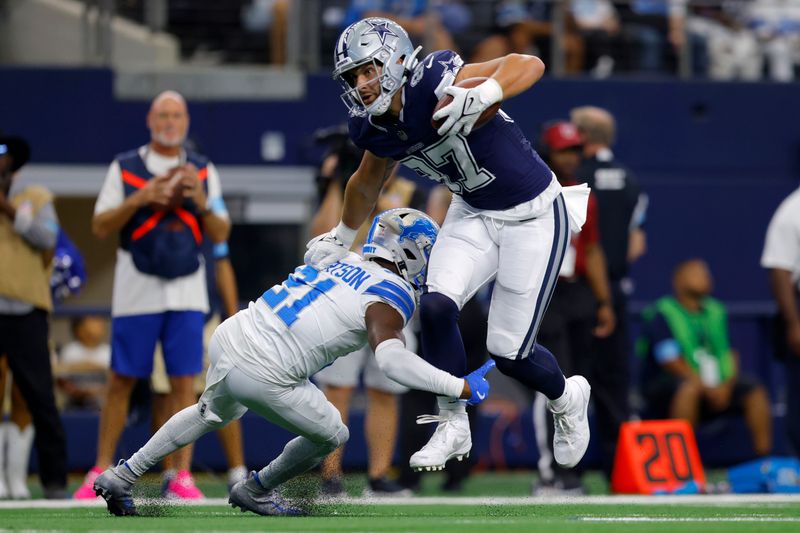 Dallas Cowboys tight end Jake Ferguson (87) attempts to escape the grasp of Detroit Lions cornerback Amik Robertson (21) after catching a pass in the first half of an NFL football game in Arlington, Texas, Sunday, Oct. 13, 2024. (AP Photo/Gareth Patterson)