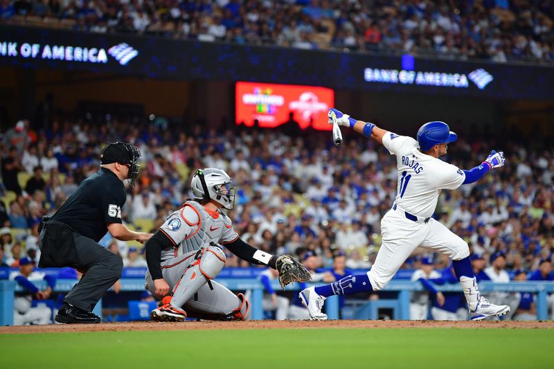 Aug 27, 2024; Los Angeles, California, USA; Los Angeles Dodgers shortstop Miguel Rojas (11) hits a sacrifice RBI against the Baltimore Orioles during the second inning at Dodger Stadium. Mandatory Credit: Gary A. Vasquez-USA TODAY Sports