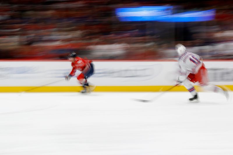 Jan 4, 2025; Washington, District of Columbia, USA; Washington Capitals left wing Jakub Vrana (13) and New York Rangers defenseman Urho Vaakanainen (18) chase the puck in the first period at Capital One Arena. Mandatory Credit: Geoff Burke-Imagn Images