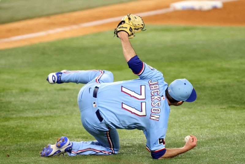 Jun 29, 2025; Arlington, Texas, USA; Texas Rangers pitcher Luke Jackson (77) fields a ground bal during the tenth inning against the Seattle Mariners at Globe Life Field. Mandatory Credit: Tim Heitman-Imagn Images