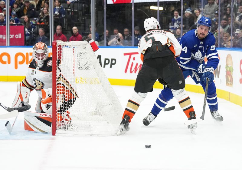 Feb 17, 2024; Toronto, Ontario, CAN; Toronto Maple Leafs center Auston Matthews (34) battles with Anaheim Ducks defenseman Urho Vaakanainen (5) behind the net during the first period at Scotiabank Arena. Mandatory Credit: Nick Turchiaro-USA TODAY Sports