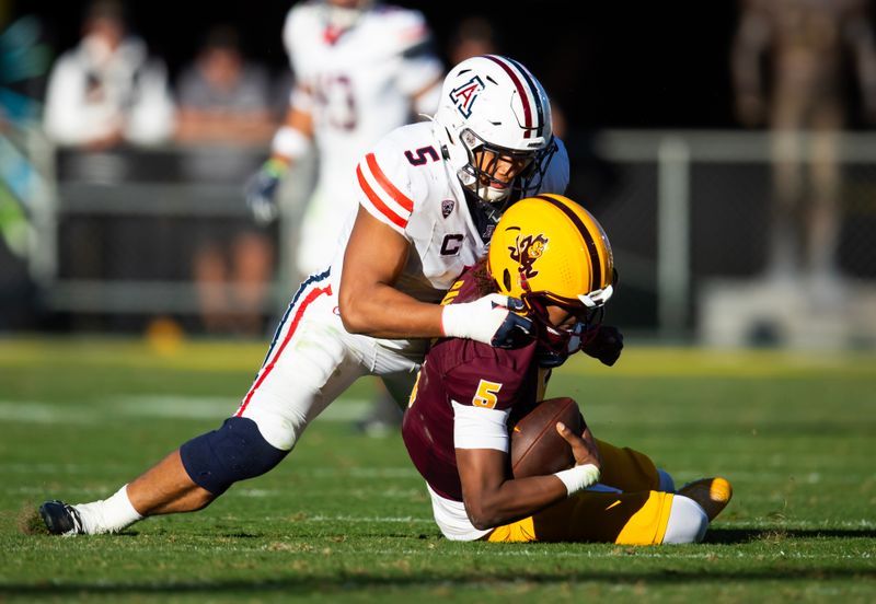 Nov 25, 2023; Tempe, Arizona, USA; Arizona Wildcats linebacker Jacob Manu (top) sacks Arizona State Sun Devils quarterback Jaden Rashada in the second half of the Territorial Cup at Mountain America Stadium. Mandatory Credit: Mark J. Rebilas-USA TODAY Sports