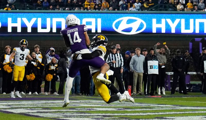 Nov 4, 2023; Chicago, Illinois, USA; Northwestern Wildcats wide receiver Cam Johnson (14) catches a touchdown on Iowa Hawkeyes defensive back Jermari Harris (27) during the second half at Wrigley Field. Mandatory Credit: David Banks-USA TODAY Sports