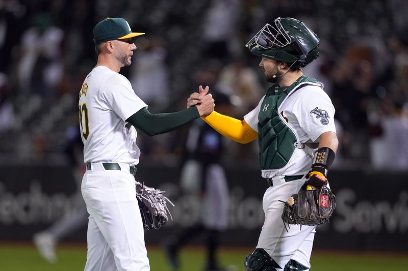 May 3, 2024; Oakland, California, USA; Oakland Athletics relief pitcher Lucas Erceg (left) and catcher Shea Langeliers (right) celebrate after defeating the Miami Marlins at Oakland-Alameda County Coliseum. Mandatory Credit: Darren Yamashita-USA TODAY Sports