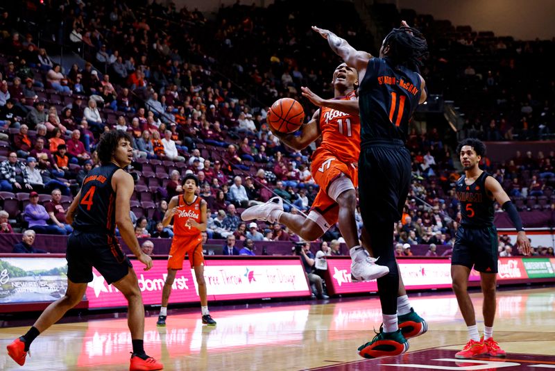 Jan 4, 2025; Blacksburg, Virginia, USA; Virginia Tech Hokies guard Ben Hammond (11) drives to the basket against Miami Hurricanes guard A.J. Staton-McCray (11) during the first half at Cassell Coliseum. Mandatory Credit: Peter Casey-Imagn Images