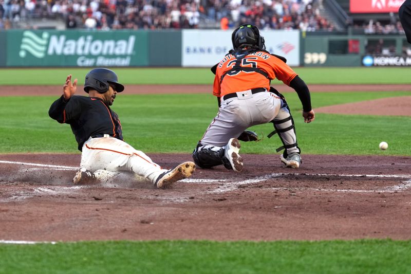 Jun 3, 2023; San Francisco, California, USA;  San Francisco Giants first baseman LaMonte Wade Jr. (31) slides into home plate to score a run as Baltimore Orioles catcher Adley Rutschman (35) waits for a throw during the third inning at Oracle Park. Mandatory Credit: Darren Yamashita-USA TODAY Sports