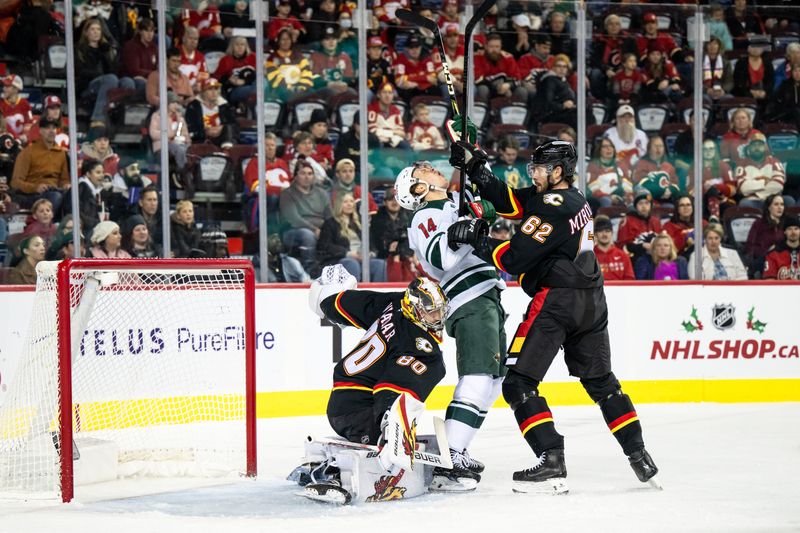 Nov 23, 2024; Calgary, Alberta, CAN; Minnesota Wild center Joel Eriksson Ek (14) takes a high stick from Calgary Flames defenseman Daniil Miromanov (62) during the first period at Scotiabank Saddledome. Mandatory Credit: Brett Holmes-Imagn Images