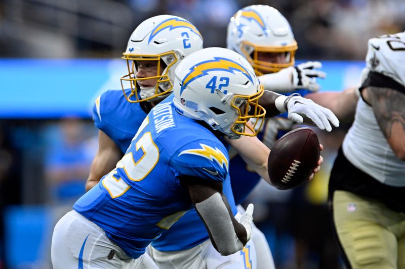 Los Angeles Chargers quarterback Easton Stick (2) faints a hand off to running back Elijah Dotson (42) against the New Orleans Saints during the first half of a preseason NFL football game Sunday, Aug. 20, 2023, in Inglewood, Calif. (AP Photo/Alex Gallardo)