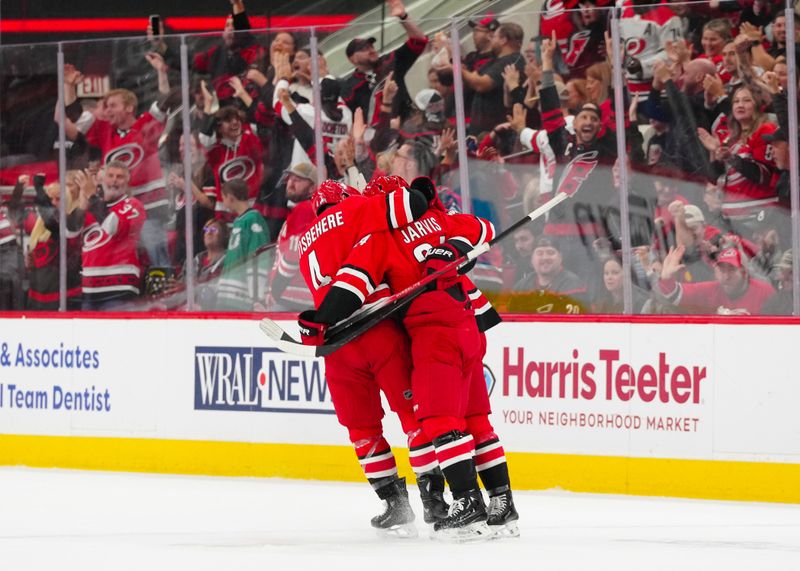 Oct 15, 2024; Raleigh, North Carolina, USA;  Carolina Hurricanes center Seth Jarvis (24) is congratulated by  defenseman Shayne Gostisbehere (4) and center Jack Drury (18) after his goal against the New Jersey Devils during the second period at PNC Arena. Mandatory Credit: James Guillory-Imagn Images