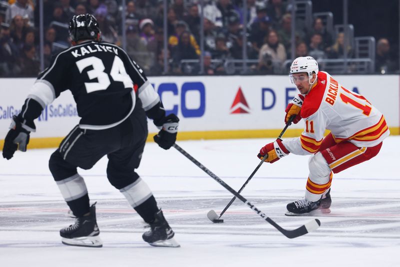 Dec 23, 2023; Los Angeles, California, USA; Calgary Flames center Mikael Backlund (11) skates with the puck during the first period against Los Angeles Kings right wing Arthur Kaliyev (34) at Crypto.com Arena. Mandatory Credit: Jessica Alcheh-USA TODAY Sports