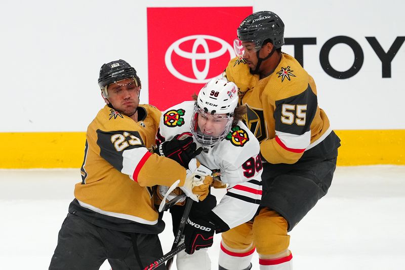 Apr 16, 2024; Las Vegas, Nevada, USA; Chicago Blackhawks center Connor Bedard (98) is checked by Vegas Golden Knights defenseman Alec Martinez (23) and right wing Keegan Kolesar (55) during the first period at T-Mobile Arena. Mandatory Credit: Stephen R. Sylvanie-USA TODAY Sports