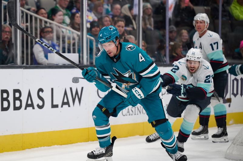 Nov 29, 2024; San Jose, California, USA; San Jose Sharks defenseman Cody Ceci (4) plays the puck against Seattle Kraken right wing Oliver Bjorkstrand (22) during the first period at SAP Center at San Jose. Mandatory Credit: Robert Edwards-Imagn Images